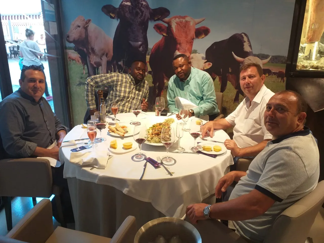 Groupe de cinq hommes réunis autour d'une table lors d'un déjeuner de travail dans un restaurant, en Espagne.